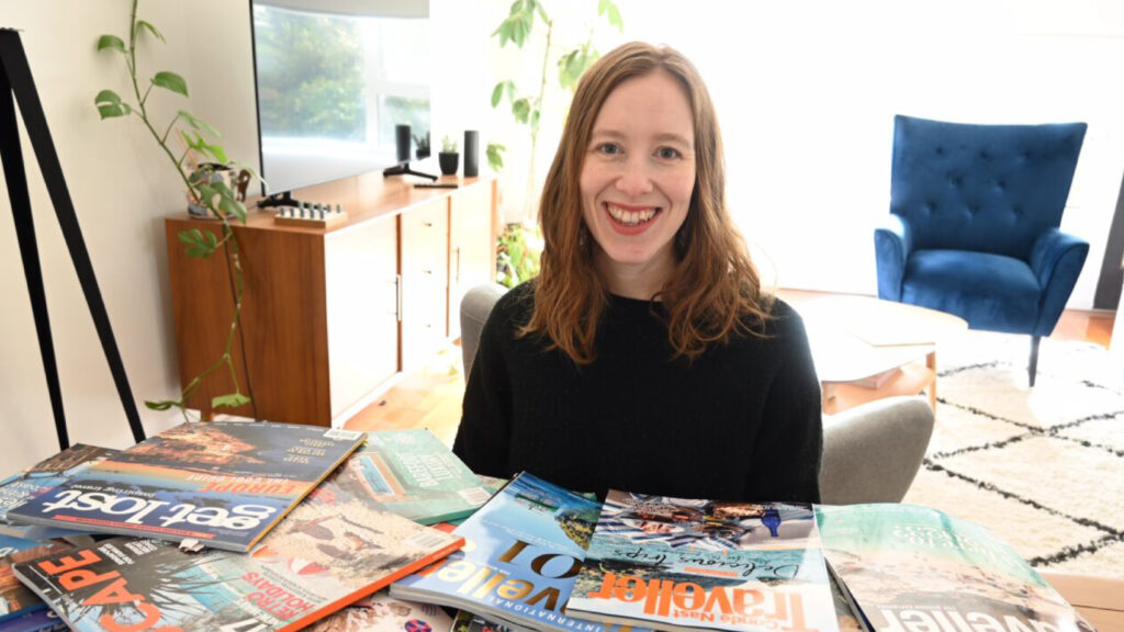 Woman sitting in front of a pile of travel magazines.