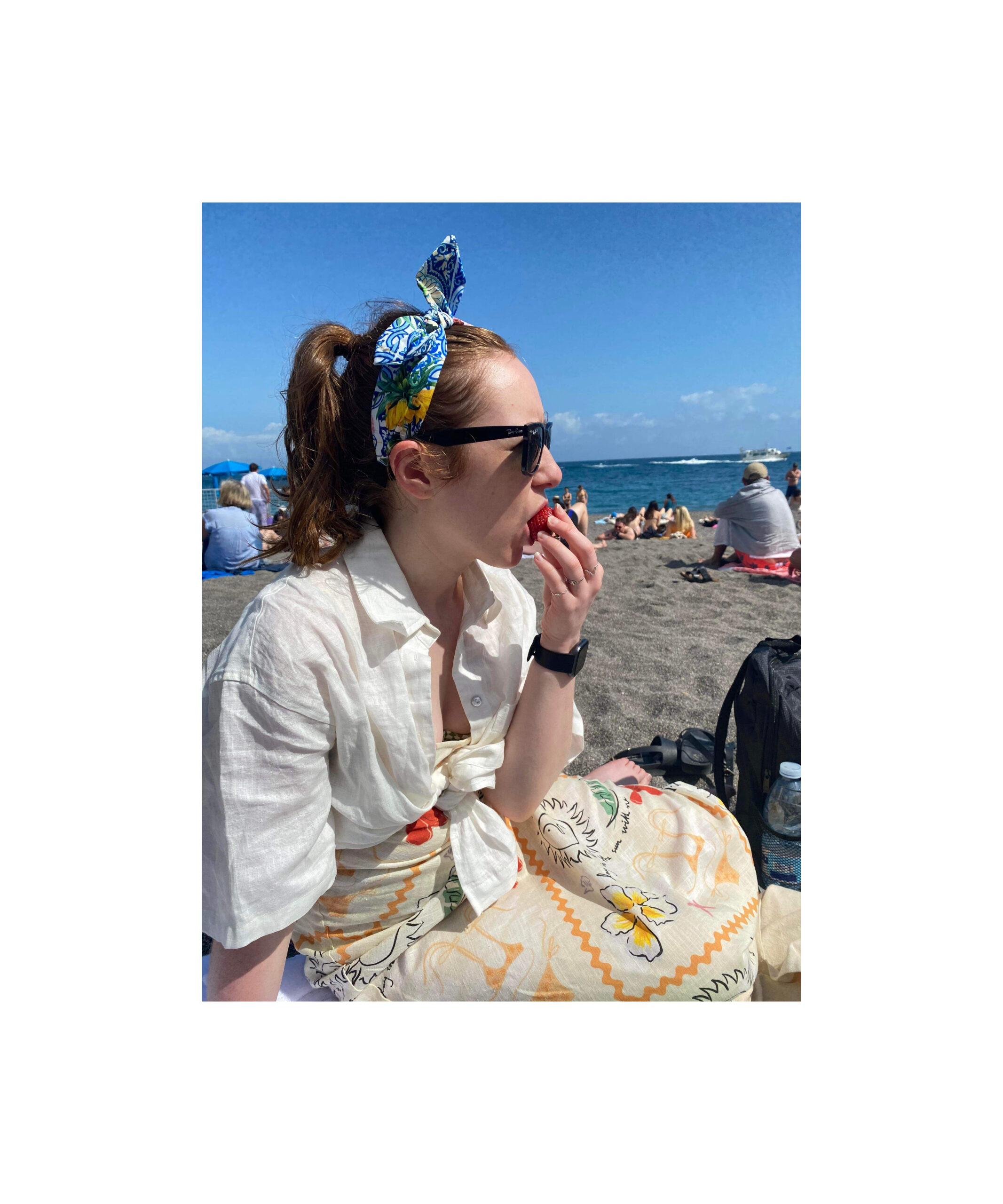 Jess on a beach eating a strawberry in Amalfi. 