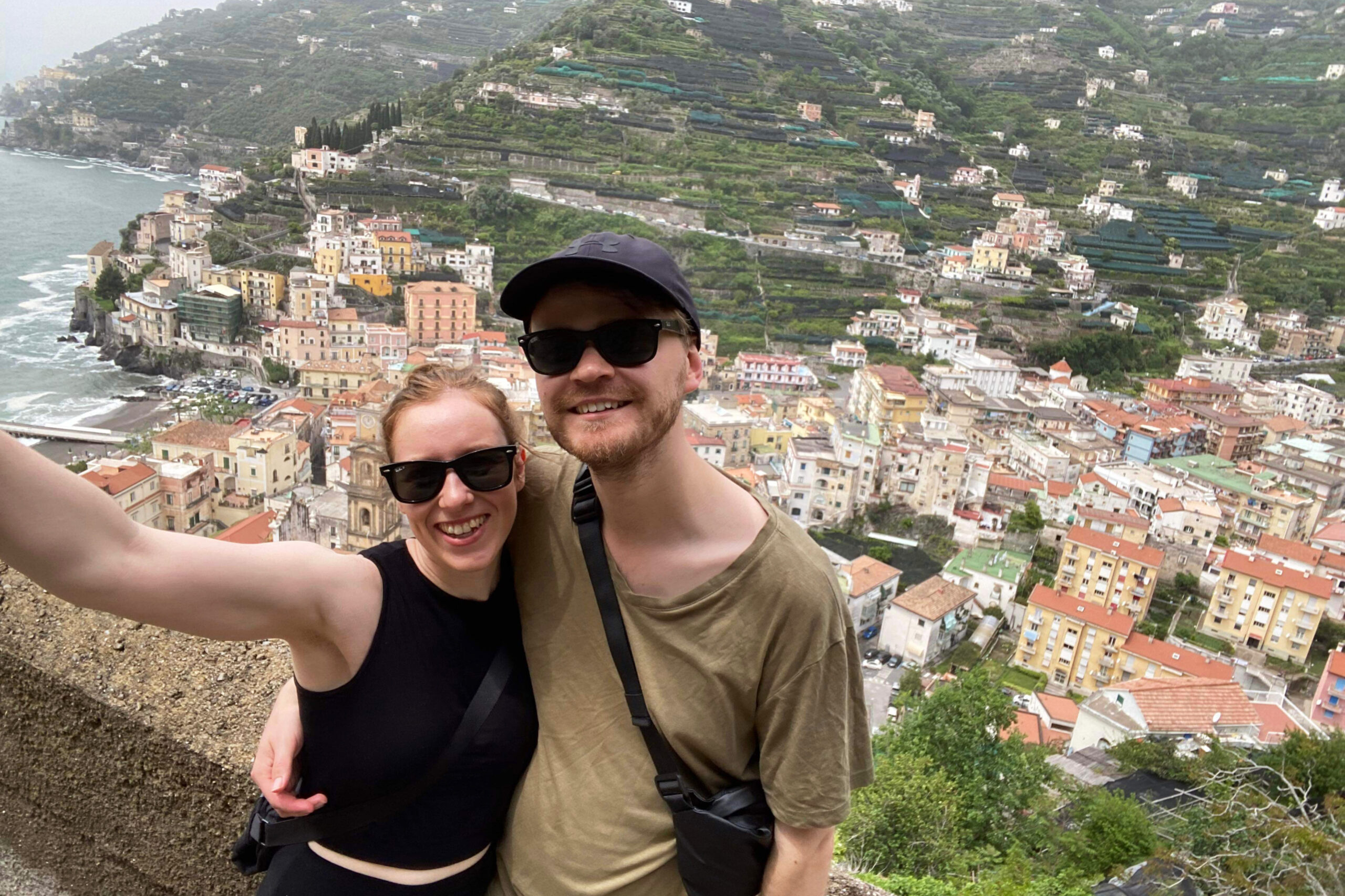 Two people posing in front of a view of the town of Minori in the Amalfi Coast. 